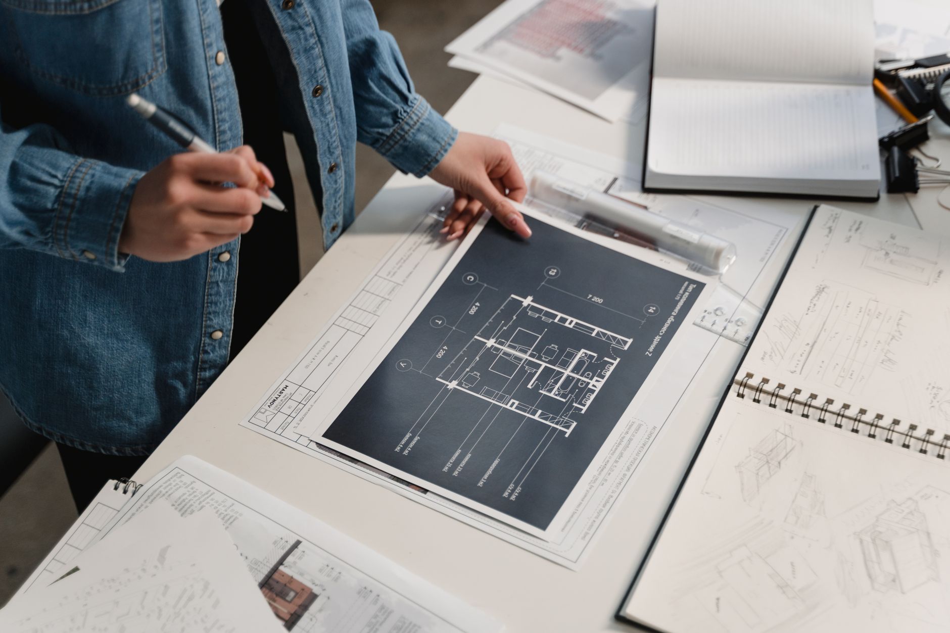 A person at a desk setting out technical plans and drawings before construction begins.